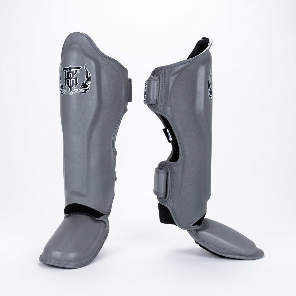 Top King TKSGP-GL Pro shin guards in black genuine leather with full-length shin and instep protection, dense impact padding and secure hook-and-loop closures for Muay Thai and kickboxing on a white background